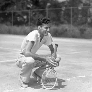 Young Man Smiling Squatting Holds Tennis Racquet A Young Man Smiling Squatting Holds Tennis Racquet A