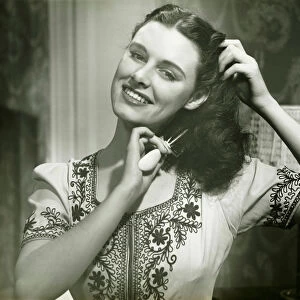 Young woman combing hair, (B&W), portrait
