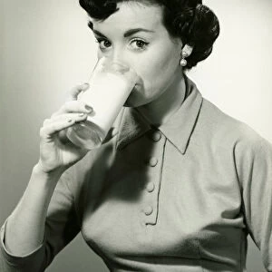 Young woman drinking glass of milk, (B&W), portrait