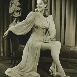 Young woman in fashionable nightdress sitting indoors, (B&W)