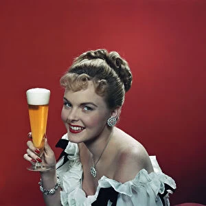 Young woman holding beer glass, smiling, portrait