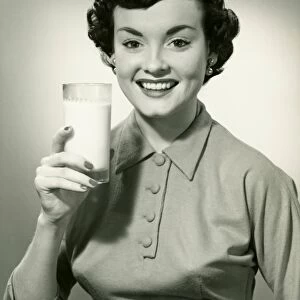Young woman holding glass of milk, (B&W), portrait