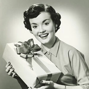 Young woman holding present, (B&W), portrait