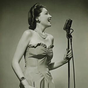 Young woman at microphone, singing, (B&W)