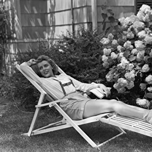 Young woman relaxing in deckchair in garden