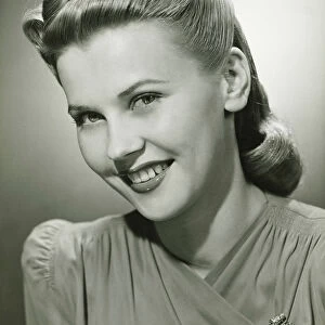 Young woman smiling in studio, (B&W), portrait