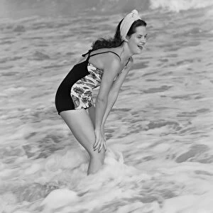 A young woman stands laughing in the surf, circa 1960. (Photo by H