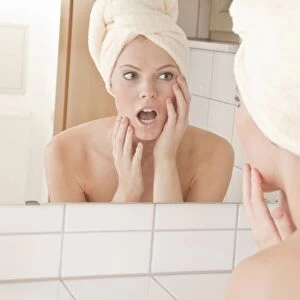 Young woman with a towel wrapped around her head in front of a mirror