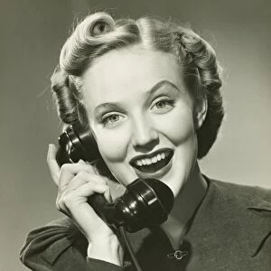 Young woman using phone, smiling, (B&W), portrait