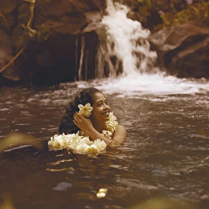 Young woman in water wearing garland and looking away