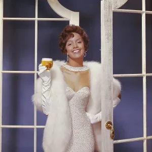 Young woman wearing fur jacket holding beer glass, smiling, portrait