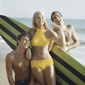 Young women and men with surfboard on beach, smiling