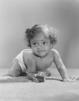 14 month old African-American baby holding alphabet block, crawling, close-up