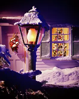 Prints of 1970s Christmas Outdoor Night Scene Snow Covered Welcome Lamppost Light And Shuttered Window With Decorated Tree Visible Inside. (Photo by Photo Media/Classicstock/Getty Images) Celebrate the Season: A Curated Collection of Christmas Art: 1970s Christmas Outdoor Nig