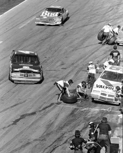 Prints of DAYTONA BEACH, FL - FEBRUARY 1986: NASCAR racecar driver Rick Wilson comes in for a pit stop as Neil Bonnett driving car No Chasing Speed: Motorsport in Motion: 1986 Daytona 500 NASCAR race