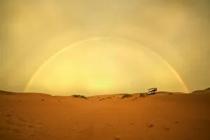 Images Dated 18th January 2005: 4X4 Vehicle on a Barren Desert Landscape Under a Rainbow