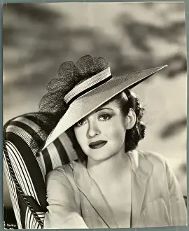Actress Bette Davis Sitting in Chair and Wearing Hat
