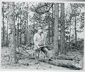 Adlai Stevenson Standing and Holding Rifle in Wooded Area