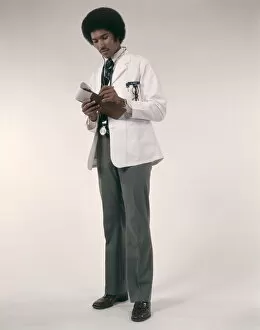 Images Dated 11th October 2005: African-American Man Doctor Wearing White Coat And Stethoscope Writing Prescriptions
