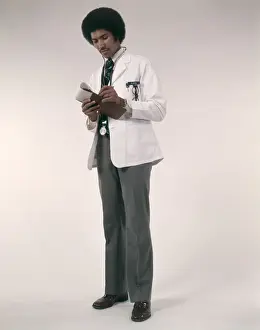 Doctor Prints: African-American Man Doctor Wearing White Coat And Stethoscope Writing Prescriptions