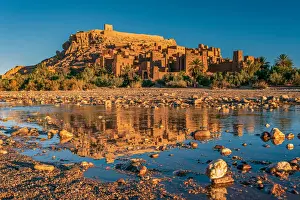 Prints of Unesco World Heritage site Ait Benhaddou in warm morning light. The old town is reflected in the calm water in the foreground. The sky is blue with no clouds Travel Destination Prints: Ait Benhaddou at sunrise