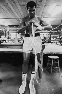 Prints of 25th August 1975: EXCLUSIVE American boxer Muhammad Ali, formerly Cassius Clay, wrapping his hands to prepare for training in a gym in Deer Lake, Pennsylvania In the Ring: The Art of Boxing: Ali In Training