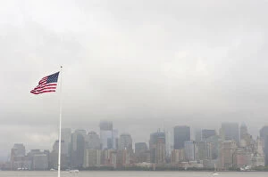 American national flag, view from Ellis Island towards the skyline of Manhattan in the fog, New York, USA
