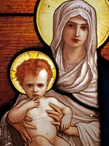 Prints of Close-up of a veiled Saint Mary, seated on a cushion, presenting the naked infant Jesus. Both wear the ring of light around their heads Dazzling Stained Glass Art Prints: Antique broken and patinated stained glass window of Saint Mary and Jesus naked