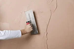 Applying a second layer of plaster to a wall using trowel