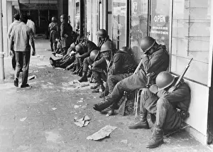 Army Guards Sleeping Against Building