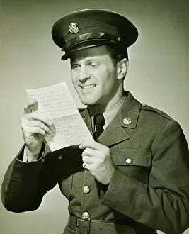 US Army solider reading letter in studio, (B&W), portrait