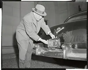 Arthur Summerfield Placing License Frames on His Car