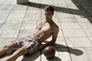 Racy Prints: Athletic young man in shorts with ball lying on a stone floor