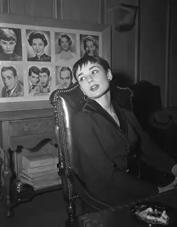 Audrey Hepburn Sitting with Wall of Portraits Behind Her