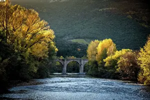 Prints of The Orb river flows down from the Massif Central in southern France near the village of Roquebrun. An ancient bridge still in use passes over the river as fall foliage glows during the setting sun Travel Imagery Prints: Autumn view along the Orb river located in the Languedoc region of southern France