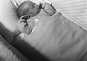 Baby (0-3 months) lying in crib, sleeping, (B&W), elevated view