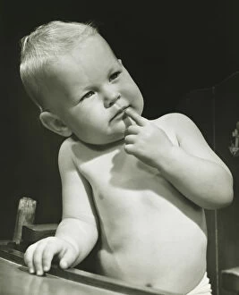 Images Dated 5th May 2006: Baby boy (6-12 months) with finger on lips sitting in high chair, (B&W), portrait