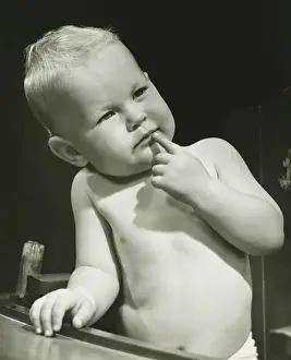 6 11 Months Prints: Baby boy (6-12 months) with finger on lips sitting in high chair, (B&W), portrait