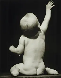 6 11 Months Prints: Baby boy (6-12 months) raising hand sitting in studio, (B&W)
