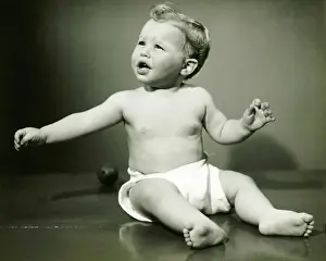 6 11 Months Prints: Baby boy (6-12) in nappy sitting on floor, (B&W)