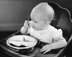 6 11 Months Prints: Baby girl (6-12 months) in high chair eating, (B&W), close-up