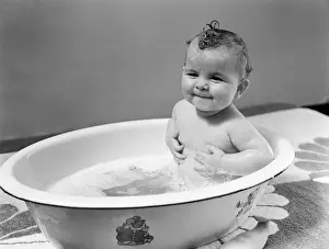 Baby sitting in bath, smiling. (Photo by H. Armstrong Roberts / Retrofile / Getty Images)