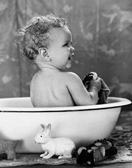 Liquid Gallery: Baby with wet hair sitting in wash basin, smiling, taking a bath
