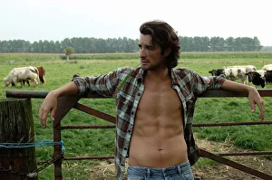 Casual Collection: Bare-chested cowboy leaning on a cow gate