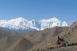 Barren hilly landscape, the snow-covered Mt Nilgiri North, 7061 m, at back, Annapurna Range near Samar, Upper Mustang