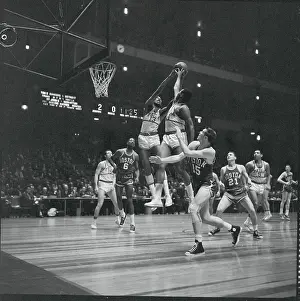 Basket Players Leap for Ball