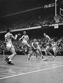 Prints of (Original Caption). Boston, Massachusetts: Celtics Bob Cousy, #14, leaps, turns, and palms ball off to teammate Tom Heinshohn (L) who scored on a lay up. St Hoops Through Time: A Visual Journey of Basketball History: Basketball Player Passing Ball to Teammate