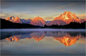 A beautiful coloured dawn casts its glow over Jackson lake in the Grand Tetons, Wyoming