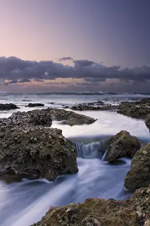 Beautiful soft colour sunrise over the sea with rocks in the foreground - Cape Vidal South Africa