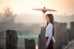 Images Dated 13th March 2016: Beautiful woman holding traditional red umbrella and walking on U Bein Bridge, Myanmar